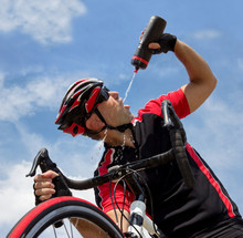 cyclist drinking from a bottle while riding a bike