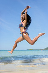 Wall Mural - Attractive woman in bikini jumping on the sea beach