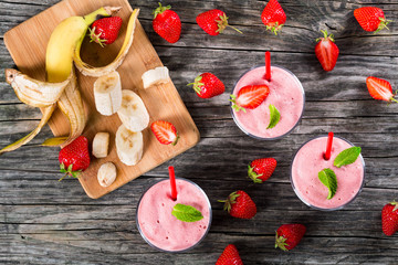 Wall Mural - Strawberry Banana milk shake Cups on an old wooden table