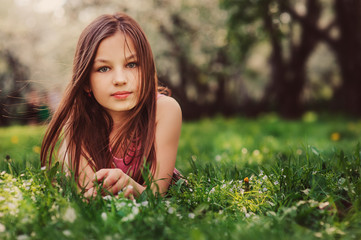 summer outdoor close up portrait of beautiful happy kid girl lying on the grass in park
