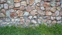 Green Grass On A Background Of Stone. 
Lawn Fence Of Stones, Sward. Background Rural Landscape. Country House
Rural House With White And Pink Stone Wall
