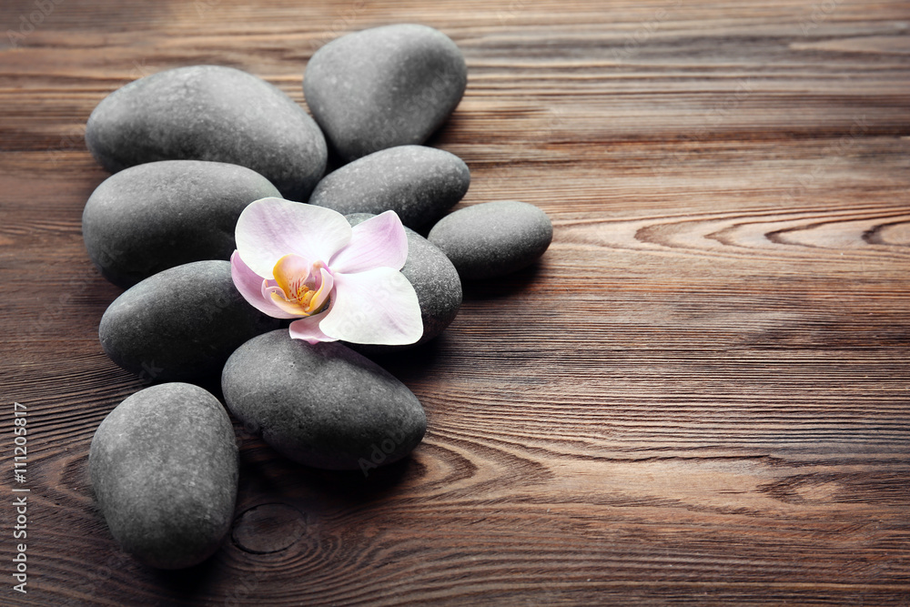 Spa stones and orchid flower on wooden background