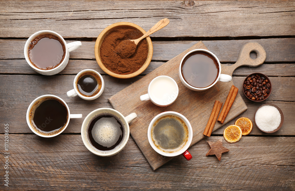 Cups of coffee with spices on wooden table, top view