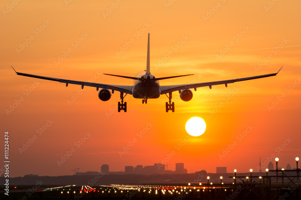 Passenger plane is landing during a wonderful sunrise. - obrazy, fototapety, plakaty 