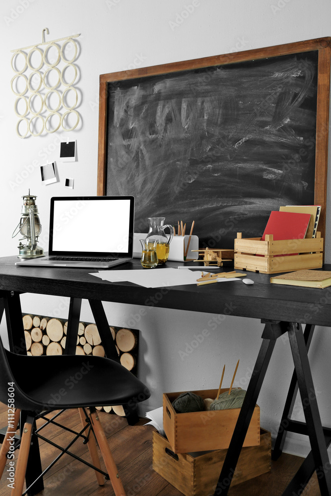 Desktop with notebook and other items on blackboard background