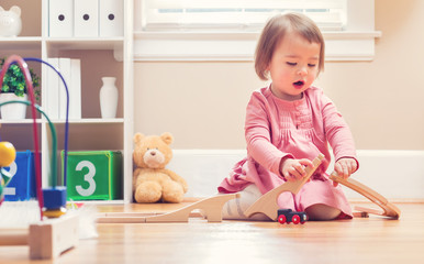 Wall Mural - Happy toddler girl playing with toys