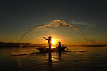 Fisherman Of Asian People At Lake In Action When Fishing During Sunrise