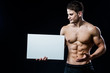 © romankosolapov - Full body bodybuilder with blank white poster isolated on black background. Handsome muscular man holding gray board copyspace in hands.