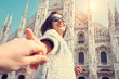 Smiling woman hold his boyfriend hand on Duomo di Milano backgro
