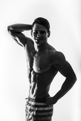 Wall Mural - Dark contrast shot young muscular fitness man stomach and arm. Bodybuilder with beads of sweat training in gym. 