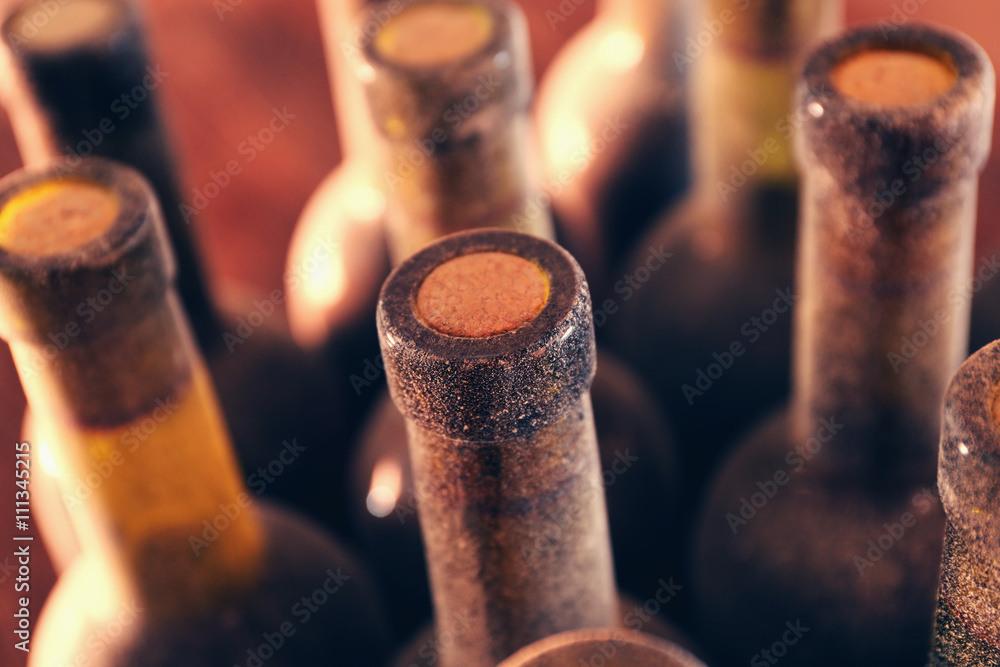 Stacks of dusty wine bottles on wooden background, upside view. Close up