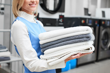 Worker Laundry girl holding fresh towels in her hands and smiles at the dry cleaners