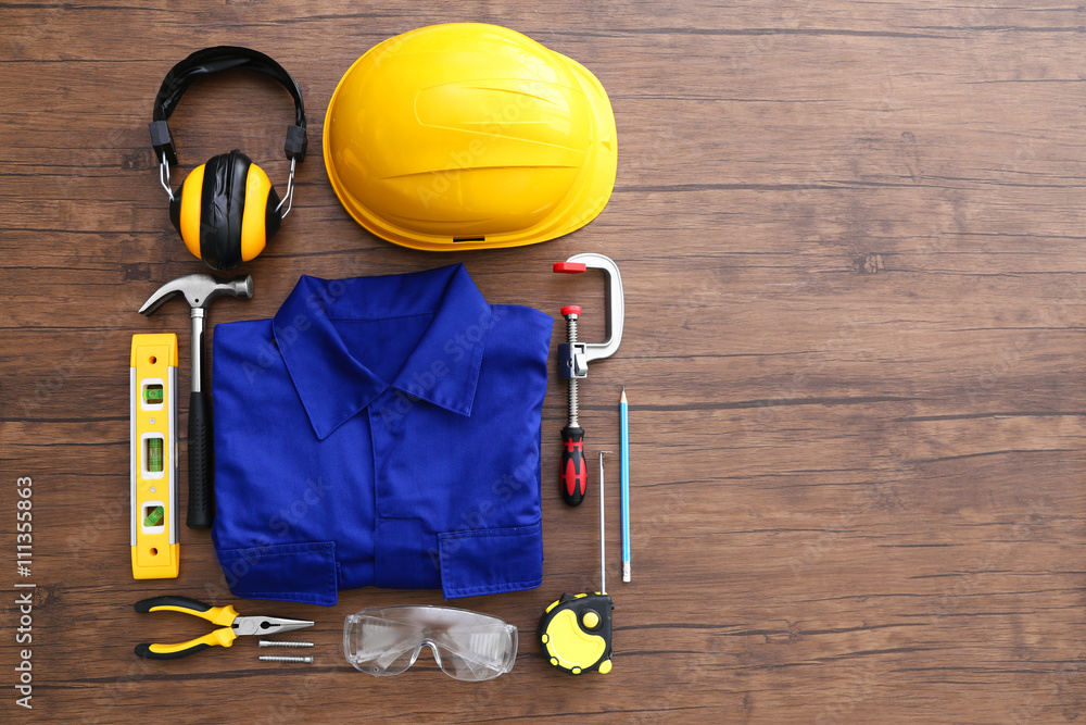 Uniform and construction tools on wooden table, top view