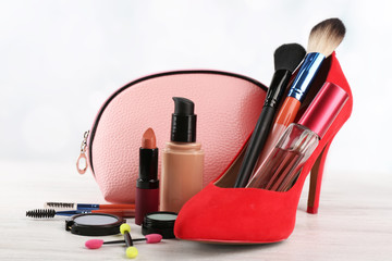 Makeup set with beautician, red woman's shoe, brushes and cosmetics on light background