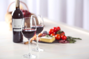 Glasses of red wine with food on blurred background