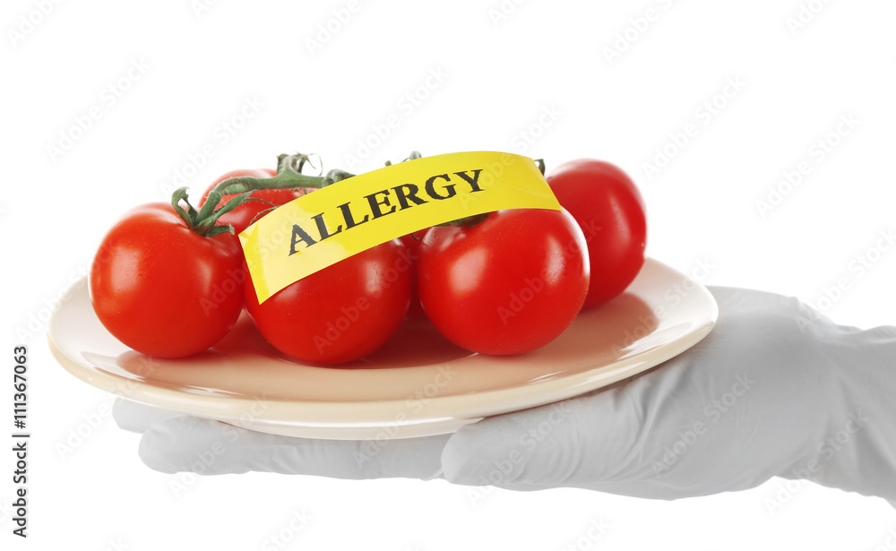 Allergic food concept. Hand in glove holding tomatoes isolated on white