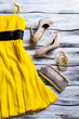 Yellow dress and heel shoes. Woman's yellow garment with footwear. Selection of stylish clothes. Wooden shelf in fashion store.