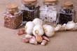 fresh garlic surrounded by containers with herbs