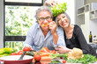 Senior couple having fun in kitchen with healthy food - Retired poeple cooking together vegetarian gourmet plate at home