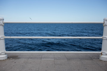 blue sea with seagull and seafront handrail