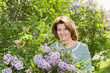 © olgavolodina - Adult woman in park near the blossoming lilac