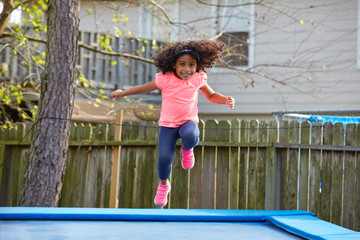 Wall Mural - Kid toddler girl jumping on a trampoline