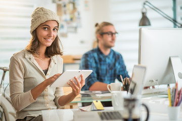 Two young colleagues working in an office, focus on the woman