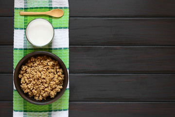 Wall Mural - Dried berry and oatmeal breakfast cereal in rustic bowl with a glass of milk, photographed overhead on dark wood with natural light