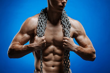 Muscular Guy With Chains On His Shoulders Against A Blue Wall