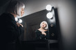 Woman in blonde wig sitting near mirror in dressing room