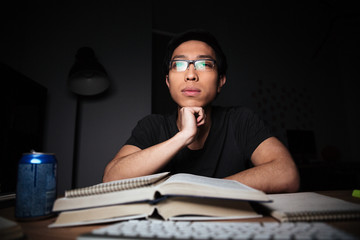 Wall Mural - Thoughtful man in glasses studying using books and computer