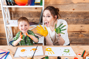 Smiling boy and mother showing hands painted in colorful paints