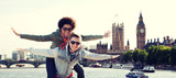 Fototapeta Londyn - happy teenage couple having fun over london city