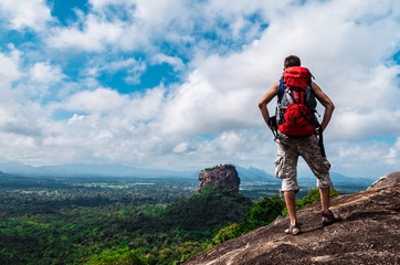 hiker with backpack enjoying views from top of a mountain. sigiriya rock, pidurangala rock, sri lank