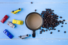 Coffee Cup With Coffee Beans And Toys Car On The Blue Wooden Bac