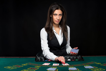 The beautiful girl, dealer, behind a table for poker