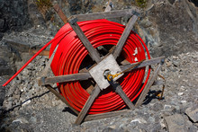 Spool Of  Red Cable And Fiber Optics In The Road Background. Building Of Road In Norway