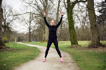 Middle aged woman exercising in autumnal park 