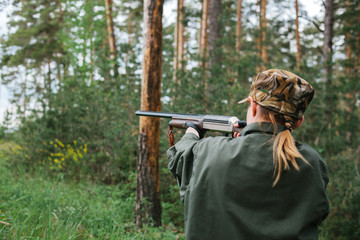 Woman hunter with a gun. Hunting in the woods.