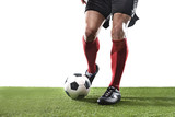 Fototapeta Sport - football player in red socks and black shoes running and dribbling with the ball playing on grass