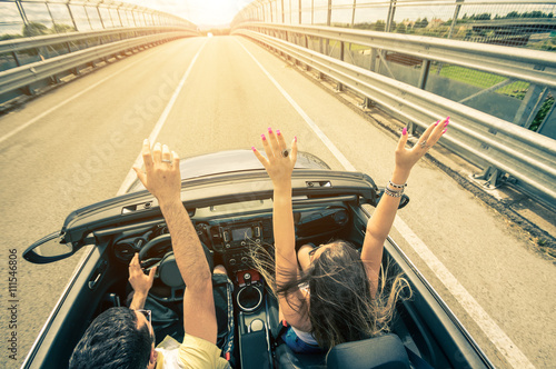 Plakat Szczęśliwa para jazdy na drodze do zachodu słońca w samochodzie sportowym