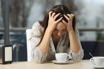 Wall Mural - Sad and depressed woman alone in a coffee shop