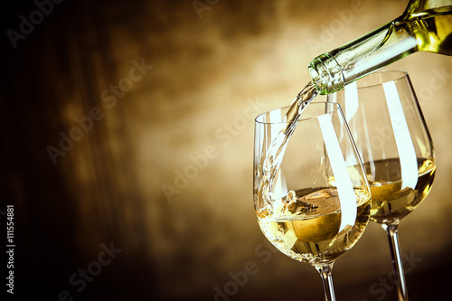 Fotografía Verter dos vasos de vino blanco de una botella