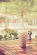 iced milk coffee in plastic cup on wooden table in tree background