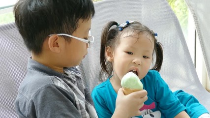 Wall Mural - Asian sibling enjoy eating ice cream together