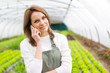 © Production Perig - Portrait of an attractive farmer in a greenhouse using mobile