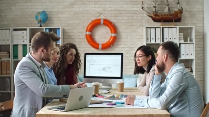 Poster - Creative young team of designers sitting at table and brainstorming to generate ideas in meeting, team leader explaining his idea, shot on Sony NEX 700 + Odyssey 7Q 