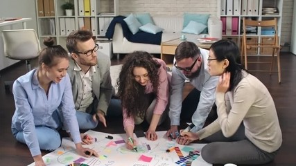 Poster - Creative young team sitting on floor and brainstorming to generate ideas, shot on Sony NEX 700 + Odyssey 7Q  