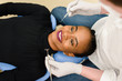 Young African-American ethnic black female smiling while dentist in white latex gloves check condition of her teeth