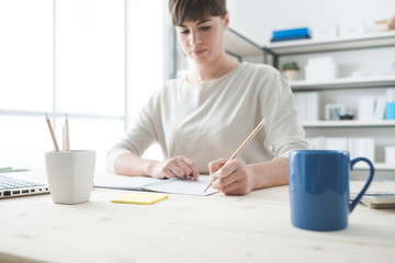 Wall Mural - Young woman sketching on a notebook